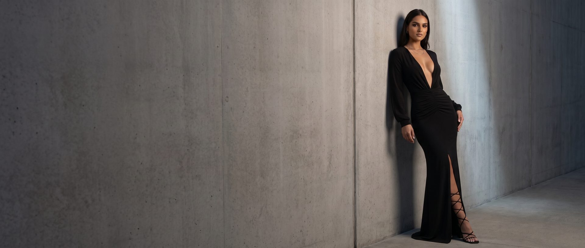 Model in a black plunge-neckline evening gown against a concrete wall at night - Marettimo After Dark